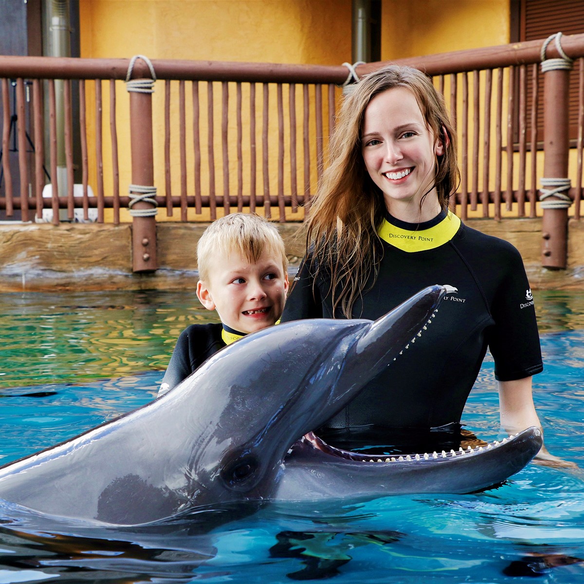 Taylor Bornman lsus computer science student poses with her son blond child and dolphin in a pool